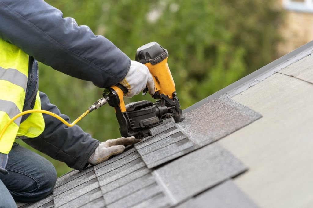 Nailing roof shingles on home in Dallas Texas.